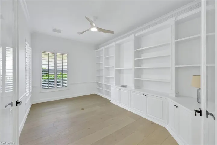 Expansive Den / office with lots of shelves and storage and a ceiling fan