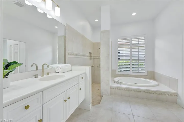 Primary bathroom featuring a garden tub, vanity, walk in shower, tile patterned floors, and recessed lighting