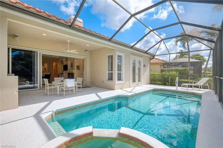 View of swimming pool featuring a patio area, a pool with connected hot tub, and a lanai