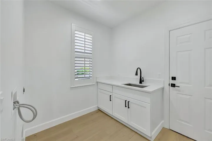 Washroom featuring light wood-type flooring, cabinet space, natural stone surface, new fixtures and hookup for a washing machine