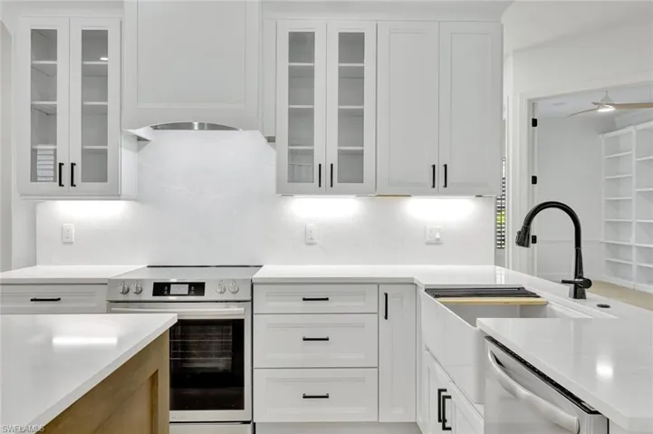 Kitchen with appliances with stainless steel finishes, light countertops, white cabinetry, and backsplash