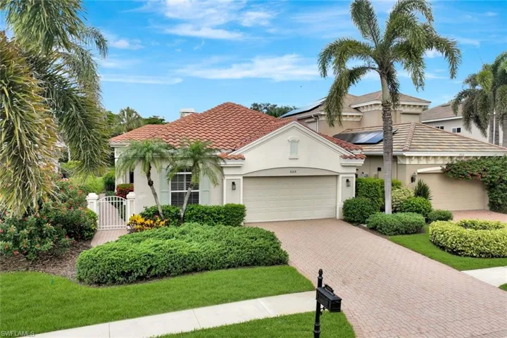 Front elevation with a gate, an attached garage, decorative driveway, a tiled roof and common sidewalk.