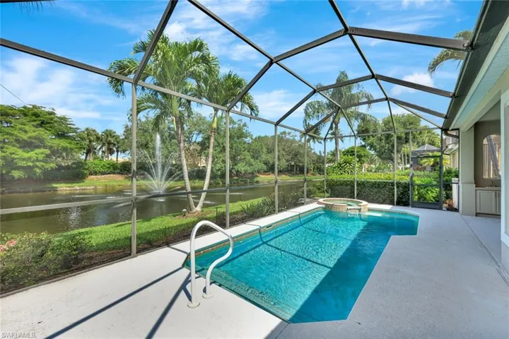View of pool with a water view, a patio area, a pool with connected hot tub, and glass enclosure