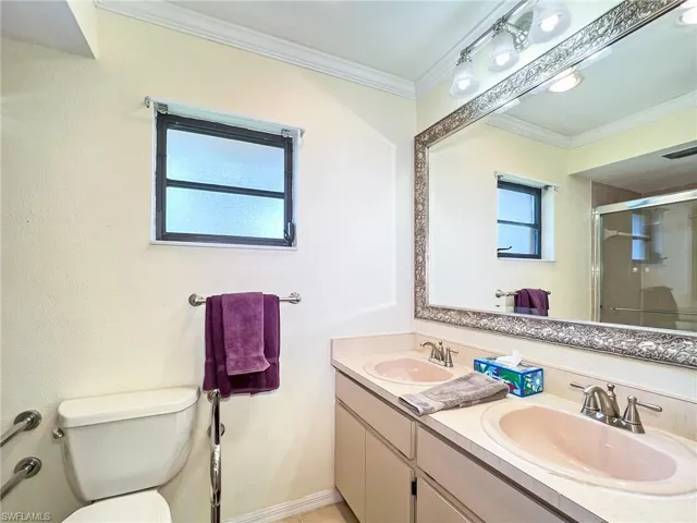 Bathroom with crown molding, toilet, vanity, and walk in shower