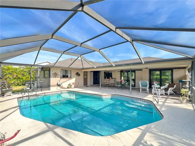 View of pool featuring glass enclosure, ceiling fan, and a patio