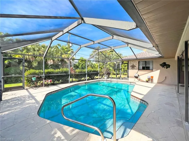 View of swimming pool with glass enclosure and a patio area