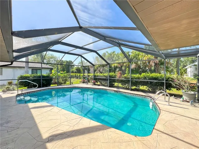 View of pool with glass enclosure and a patio area