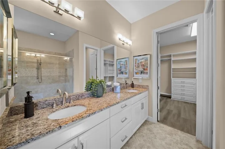 Full bath featuring double vanity, a stall shower, and a spacious closet