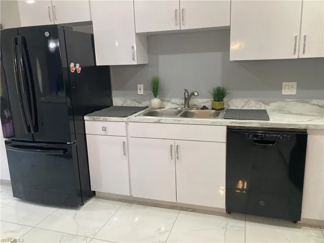 Kitchen featuring white cabinetry, sink, black appliances, and light tile floors