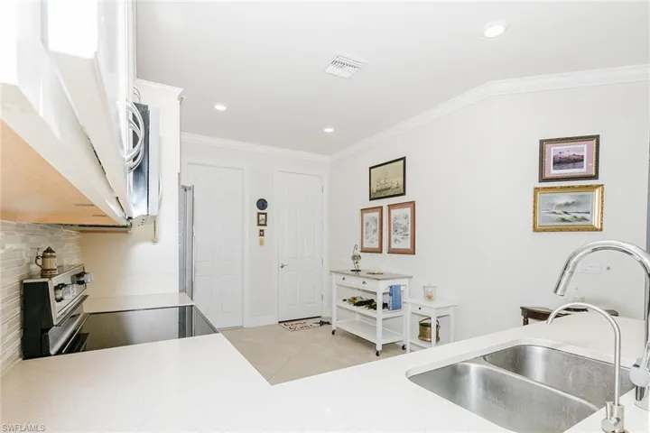 Kitchen featuring stainless steel range with electric stovetop, ornamental molding, white cabinets, light tile patterned flooring, and recessed lighting
