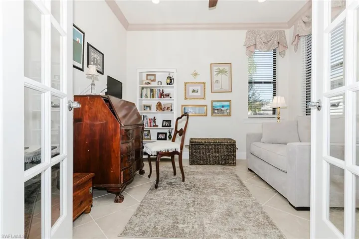 Office with ornamental molding, light tile patterned flooring, and a ceiling fan