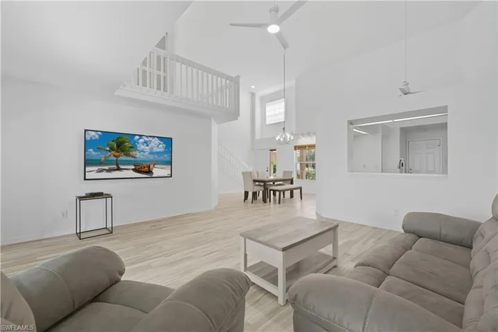 Living area with a high ceiling, light wood-style flooring, ceiling fan, recessed lighting, and a chandelier