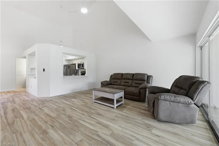 Spacious living area featuring wood-finish flooring, vaulted ceilings, and a ceiling fan