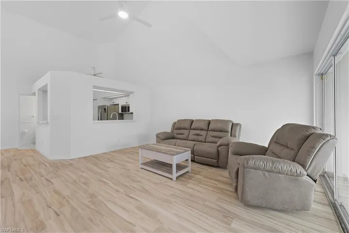 Living room featuring high vaulted ceiling, light wood-style flooring, and ceiling fan