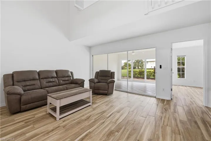 Spacious living area featuring wood-finish flooring, soaring ceilings, and white walls
