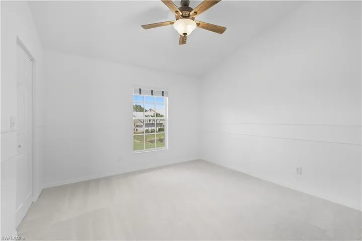 Unfurnished bedroom featuring light carpet, lofted ceiling, a closet, and a ceiling fan