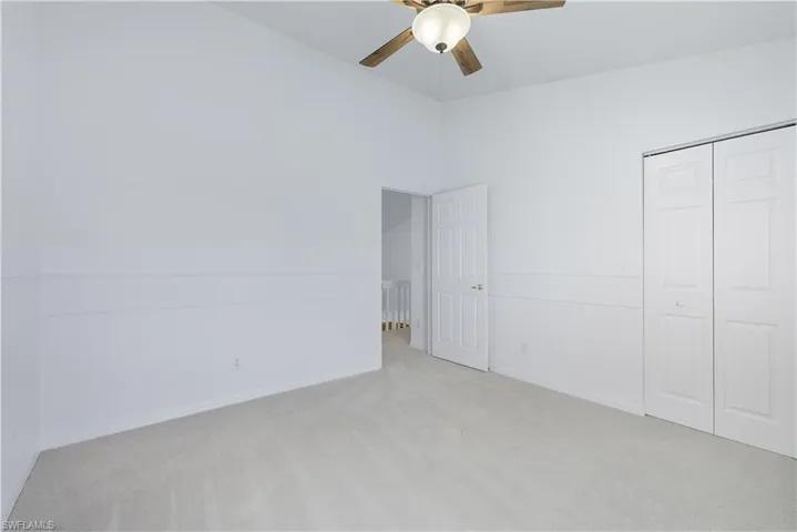 Unfurnished bedroom featuring carpet flooring, a closet, and a ceiling fan