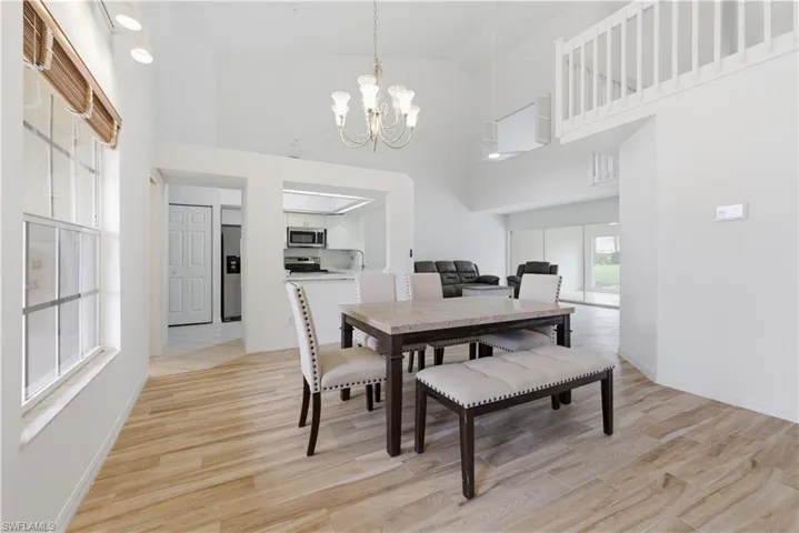 Vaulted ceilings accent this open-concept dining area featuring wood-finish flooring