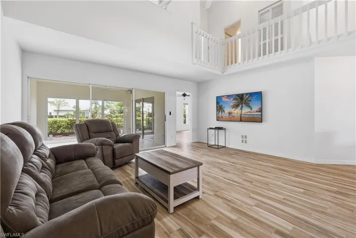 Spacious living area featuring high ceilings, wood-finish flooring, and white painted walls