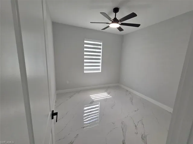 Room featuring sleek marble-look tile flooring, a modern black ceiling fan with integrated lighting, and a window with horizontal blinds