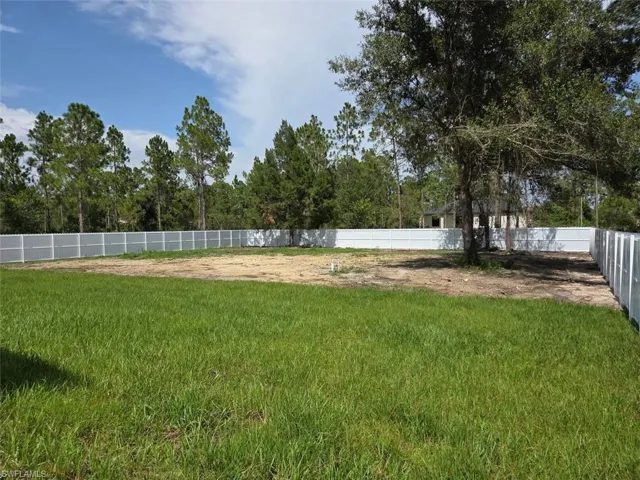 Expansive fenced yard featuring a mix of established grass and cleared land