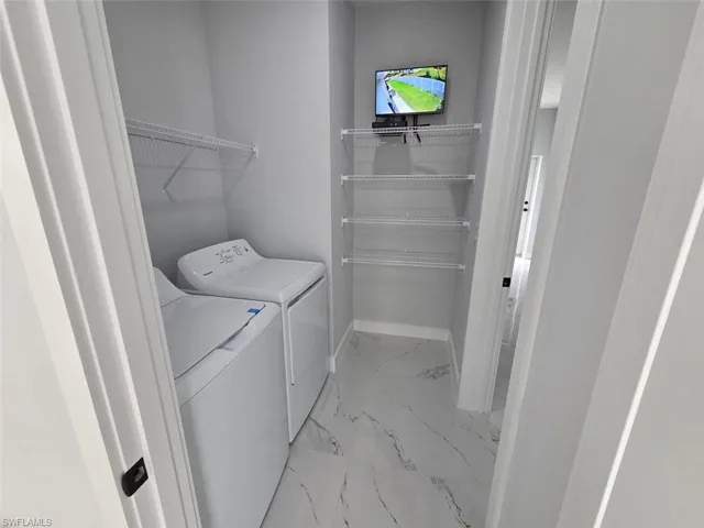 Dedicated laundry area featuring white appliances, a top-mounted wire shelf, and multiple wire shelving units