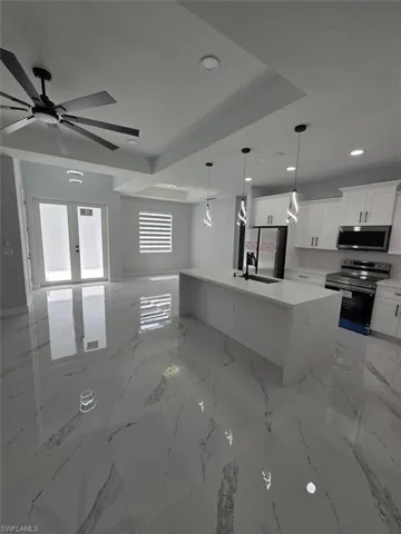 Contemporary kitchen featuring a large island with integrated sink, white cabinetry, and stainless steel appliances