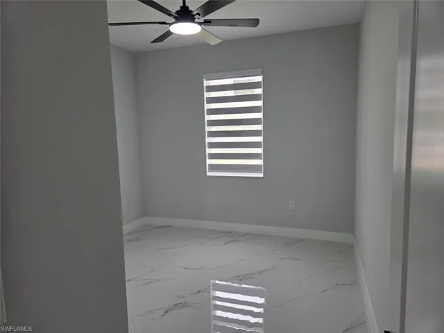 Room with white tile flooring, baseboard trim, and a window with horizontal blinds