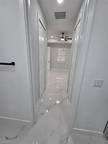 Hallway featuring polished tile flooring, two paneled doors, and ceiling-mounted lighting