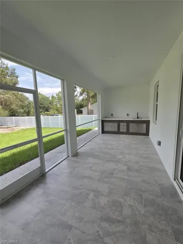 Screened lanai featuring large format tile flooring, built-in cabinetry with a countertop, and a basin sink with a wall-mounted faucet