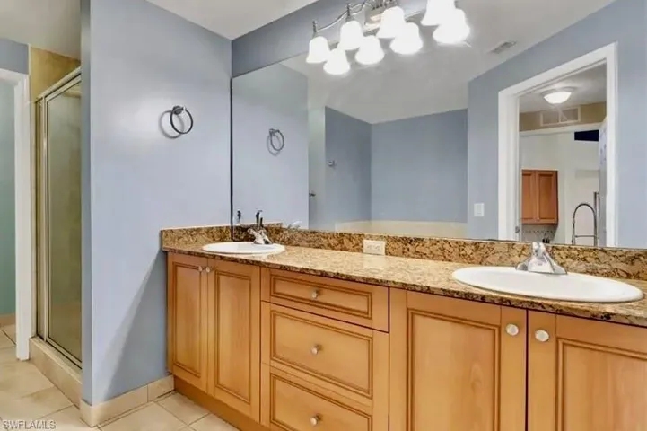 Full bath featuring double vanity, a stall shower, and light tile patterned floors