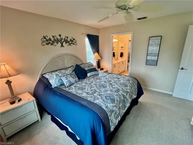 Carpeted bedroom featuring visible vents, baseboards, connected bathroom, and a ceiling fan