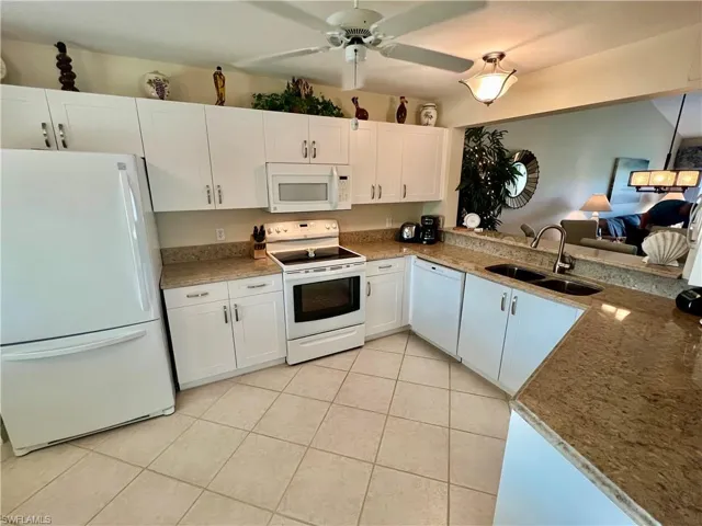 Kitchen featuring a ceiling fan, a sink, white cabinetry, white appliances, and light tile patterned floors
