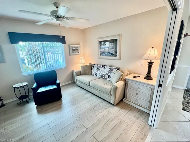 Living area featuring a ceiling fan, light wood-style floors, and baseboards