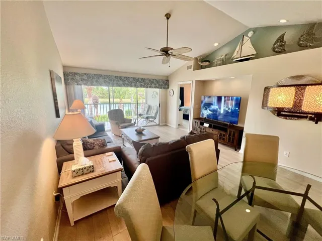 Living area with visible vents, ceiling fan, baseboards, vaulted ceiling, and light wood-style floors