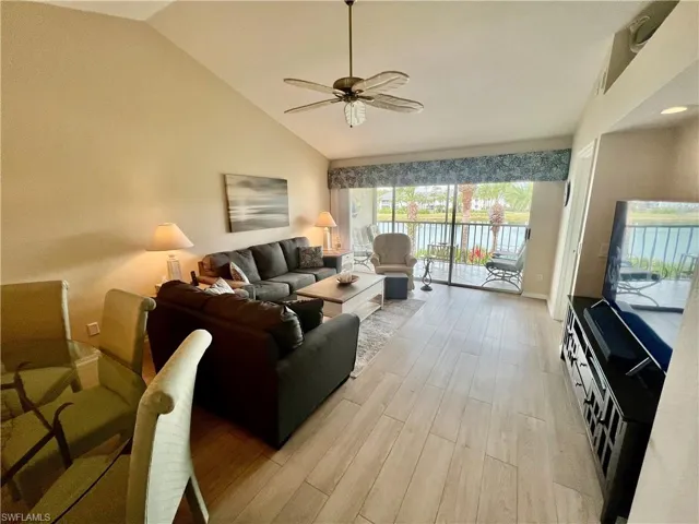 Living room with high vaulted ceiling, light wood-type flooring, and a ceiling fan