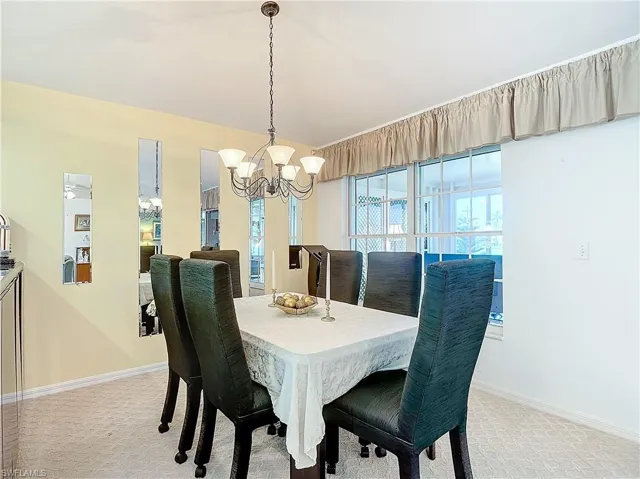 Dining space with light carpet and a chandelier