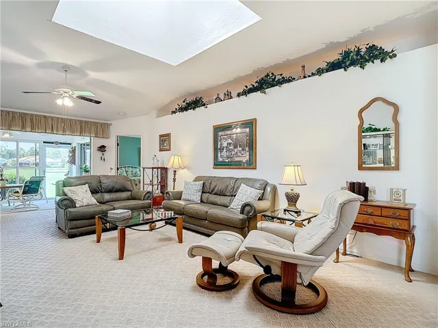 Living room featuring ceiling fan, lofted ceiling looking out back.
