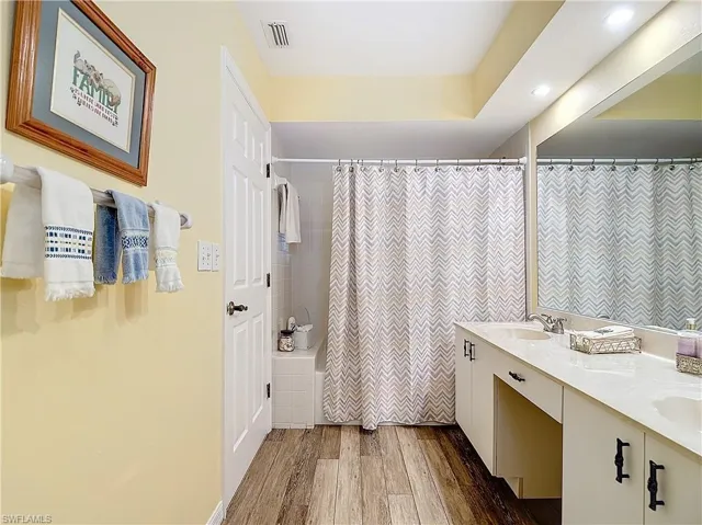 Guest Bathroom featuring double sink vanity, shower/tub, luxury vinyl flooring