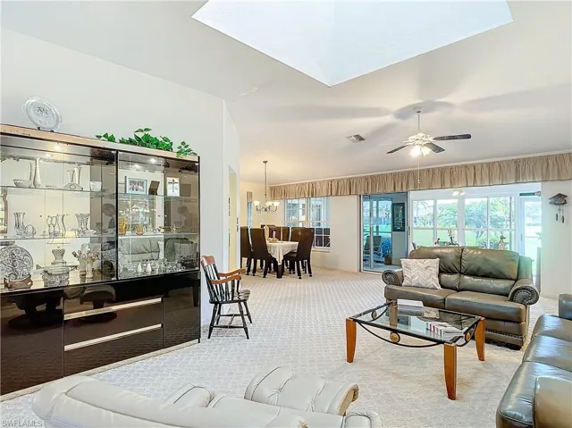 Carpeted living room and dining room view and skylight