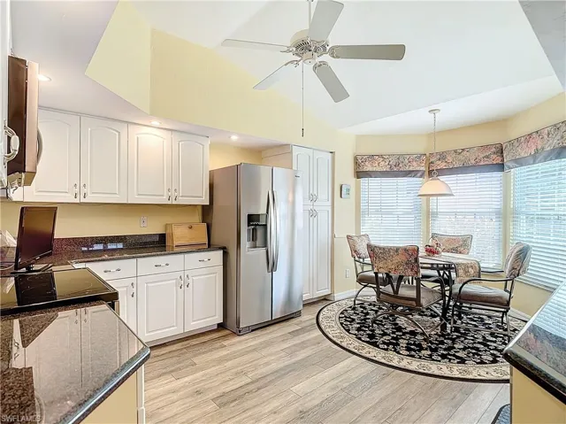 Kitchen with ceiling fan, white cabinets, hanging light fixtures, stainless steel fridge, and luxury vinyl floor