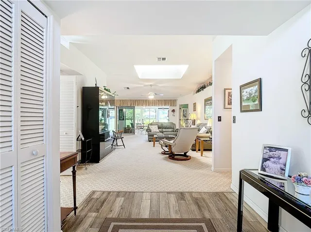 Carpeted living room featuring ceiling fan and a skylight