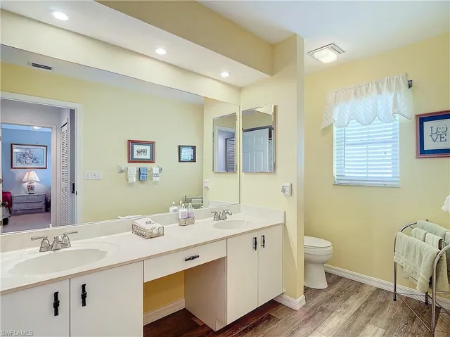 Guest Bathroom featuring luxury vinyl flooring, double vanity, and toilet