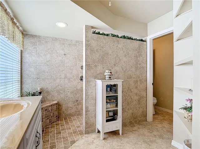 Master Bathroom with tile walls, toilet, vanity, tile patterned flooring, and handicap wheelchair accessible  shower