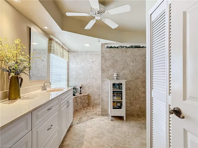 Master Bathroom featuring tile walls, double sink vanity, tile patterned flooring, and ceiling fan