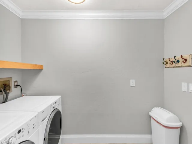 Laundry area with washer and clothes dryer and crown molding