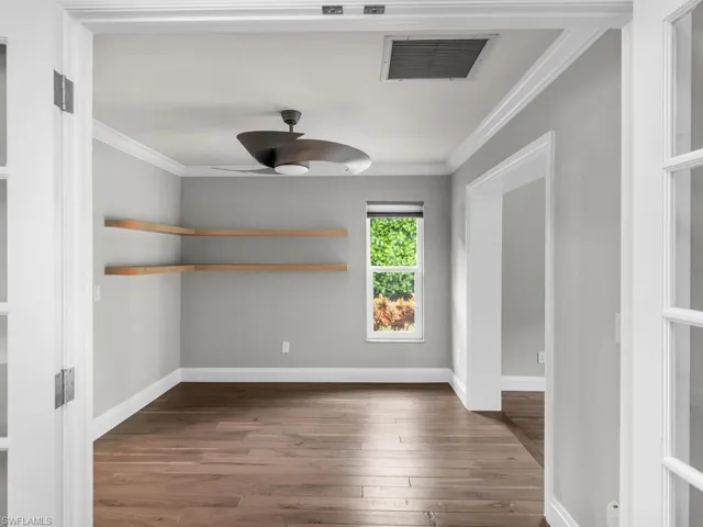Unfurnished room with dark wood-type flooring, ceiling fan, and crown molding
