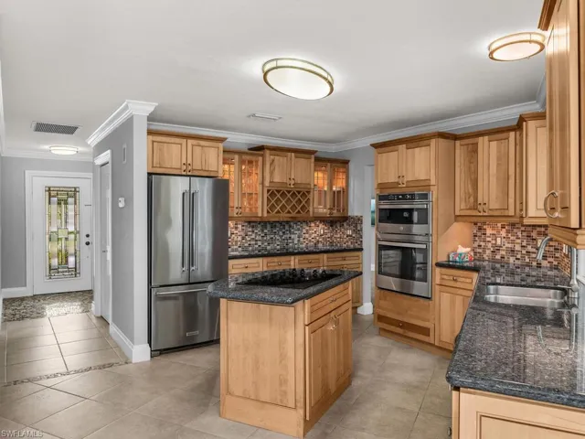 Kitchen featuring ornamental molding, appliances with stainless steel finishes, sink, and a kitchen island