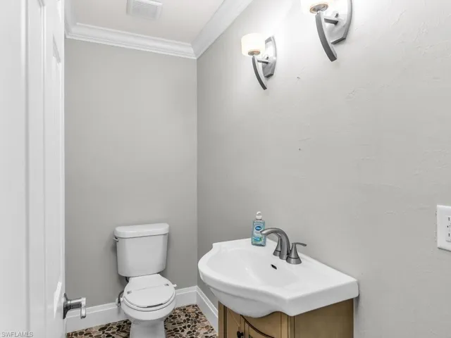 Bathroom featuring toilet, vanity, tile patterned floors, and crown molding