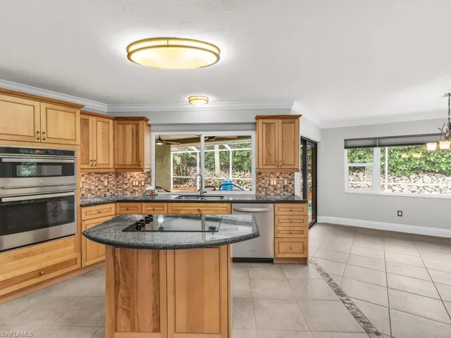 Kitchen with a wealth of natural light, appliances with stainless steel finishes, tasteful backsplash, and a center island